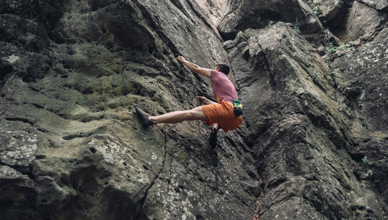 Free climber man climbing on stone rock